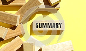 SUMMARY text written on a wooden blocks on a yellow background.