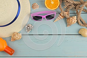 summer accessories. beach accessories. sunscreens, a hat, shells, and sunglasses on a blue wooden table. top view. place for text