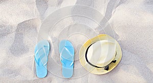 Summer accessories on beach texture banner background. Flip flops and hat on sand top view. Slippers shoes and vacation holiday