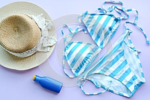 Summer accessories and blue swimming wear bikini, Sunglasses and hat for travelling at beach. Pink pastel colorful background.