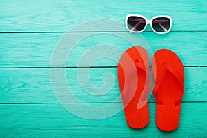 Flip flops, sunglasses. Summer accessories and copy space on blue wooden background. Top view