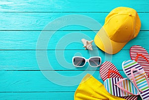 Summer accessories. Cap, sunglasses, flip flops, shell and oranges on blue wooden background. Top view and copy space