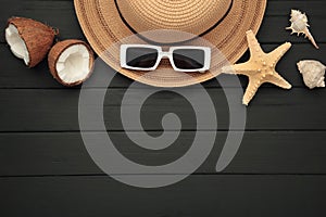 Summer accessories with coconuts on black wooden background