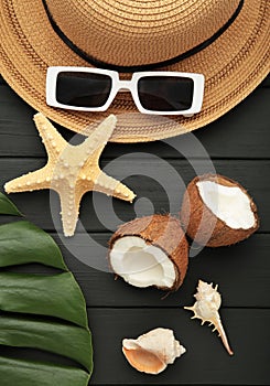 Summer accessories with coconuts on black wooden background. Vertical photo