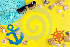 summer accessories with sun glasses, a hat and shells, on a bright yellow background. top view. space for text
