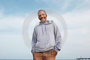 Summer active sports concept. Smiling happy young African-American man hipster in sport hoody on the beach.