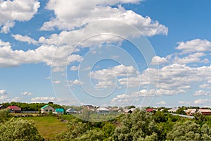 Summer afternoon over a Russian village. Beautiful white clouds in the blue sky over the Russian village