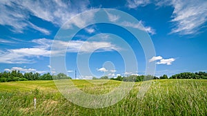 summer agricultural landscape. a hilly field under a blue cloudy sky