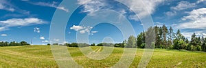 summer agricultural landscape. panoramic view of a hilly field under a blue cloudy sky