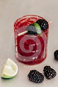 Summer alcoholic cocktail garnished with blackberries and lime