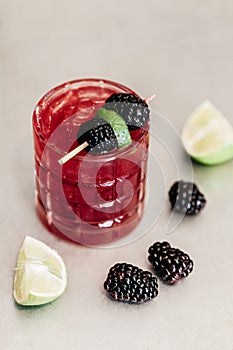 Summer alcoholic cocktail garnished with blackberries and lime