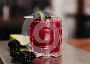 Summer alcoholic cocktail garnished with blackberries and lime