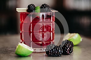 Summer alcoholic cocktail garnished with blackberries and lime