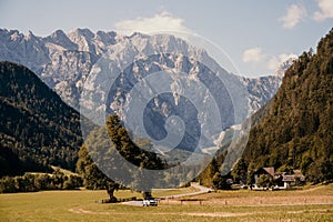 Summer alpine countryside landscape with high mountains and farms in the forest glade. Logar valley Logarska Dolina from the pan