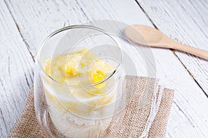 Summer appetizer of Thailand concept. Durian and sticky rice with coconut milk cream in transparent glass on white wooden table