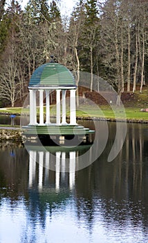 A summer arbour with white columns is ashore lake