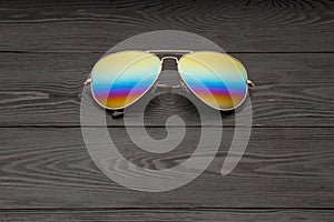 Summer aviator sunglasses with mirrored color lenses made of glass in a metal frame of gold color on a black background