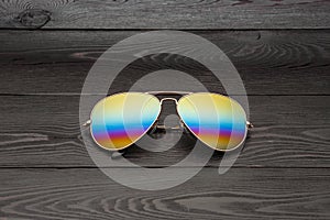 Summer aviator sunglasses with mirrored color lenses made of glass in a metal frame of gold color on a black background