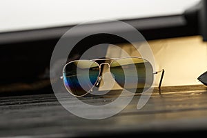 Summer aviator sunglasses with mirrored color lenses made of glass in a metal frame of gold color on a black background