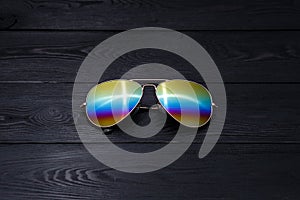 Summer aviator sunglasses with mirrored color lenses made of glass in a metal frame of gold color on a black background