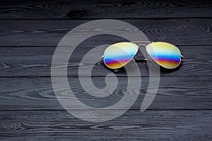 Summer aviator sunglasses with mirrored color lenses made of glass in a metal frame of gold color on a black background