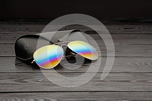 Summer aviator sunglasses with mirrored color lenses made of glass in a metal frame of gold color with a black leather case on a