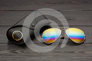 Summer aviator sunglasses with mirrored color lenses made of glass in a metal frame of gold color with a black leather case on a