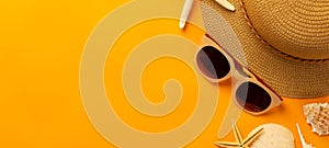 Summer background with beach accessories - straw hat, sunglasses on vibrant orange banner background.