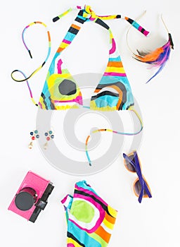 Summer background, beach outfit, girl summer stuff. Geometric abstract pattern swimsuit, pink retro camera, bright