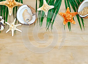 Summer background with beach sand, starfish coconut leaves, and shell decoration hanging on wooden background