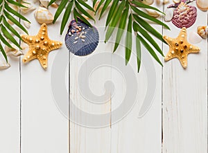 Summer background with beach sand, starfish coconut leaves, and shell decoration hanging on wooden background