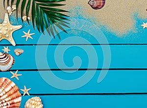 Summer background with beach sand, starfish coconut leaves, and shell decoration hanging on wooden background