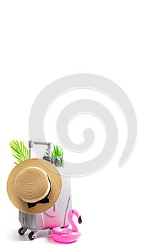 Summer background beach. Suitcase, sunglasses and pink flamingo with palm leaves and straw hat in travel composition isolated on