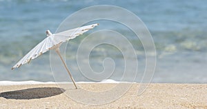 Summer background. Beach umbrella on sandy shore and blue sea. Summer vacation, dream holiday, wellness, copy space