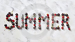 Summer background with summer berries - word `SUMMER` from cherry, raspberry, blueberries on gray stone background.