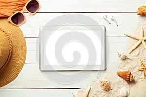 Summer background with blank screen tablet computer and beach accessories - straw hat, sunglasses on white wood table background