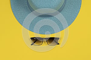 Summer background. Blue hat and sunglasses against yellow background.