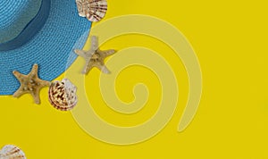 Summer background. Blue sun hat and seashells on a yellow background.
