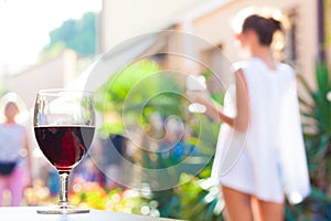 Summer background of blurred flowers and wine and wooden table place and woman