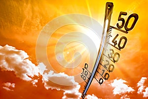Summer background, bright sun on dramatic sky with thermometer