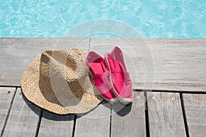 Summer background with hat shoes on the wooden deck and pool