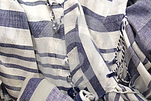 Summer background of open weave blue and white striped fabric with tassels - scrunched with selective focus