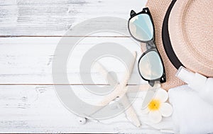 Summer background,straw hat ,towel,ear phone and sunglasses with star fish on white wood table