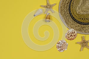 Summer background. Straw sun hat and seashells on a yellow background.