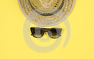 Summer background. Straw sun hat and sunglasses on a yellow background.