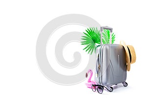 Summer background table. Suitcase, sunglasses, flamingo with palm leaves and straw hat in travel composition isolated on white