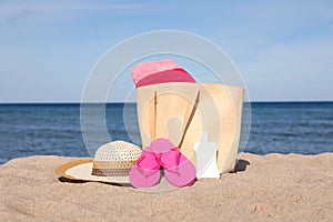 Summer bag with beach accessories on sand near sea