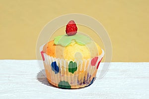 Summer baking - delicious homemade muffin with berries in colorful paper cup, decorated with marzipan cloverleaf and strawberry
