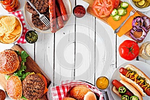 Summer BBQ food frame with hot dog and hamburger buffet, overhead against a white wood background