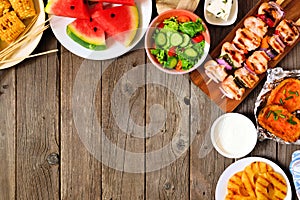 Summer BBQ or picnic food corner border, top view over a wood background